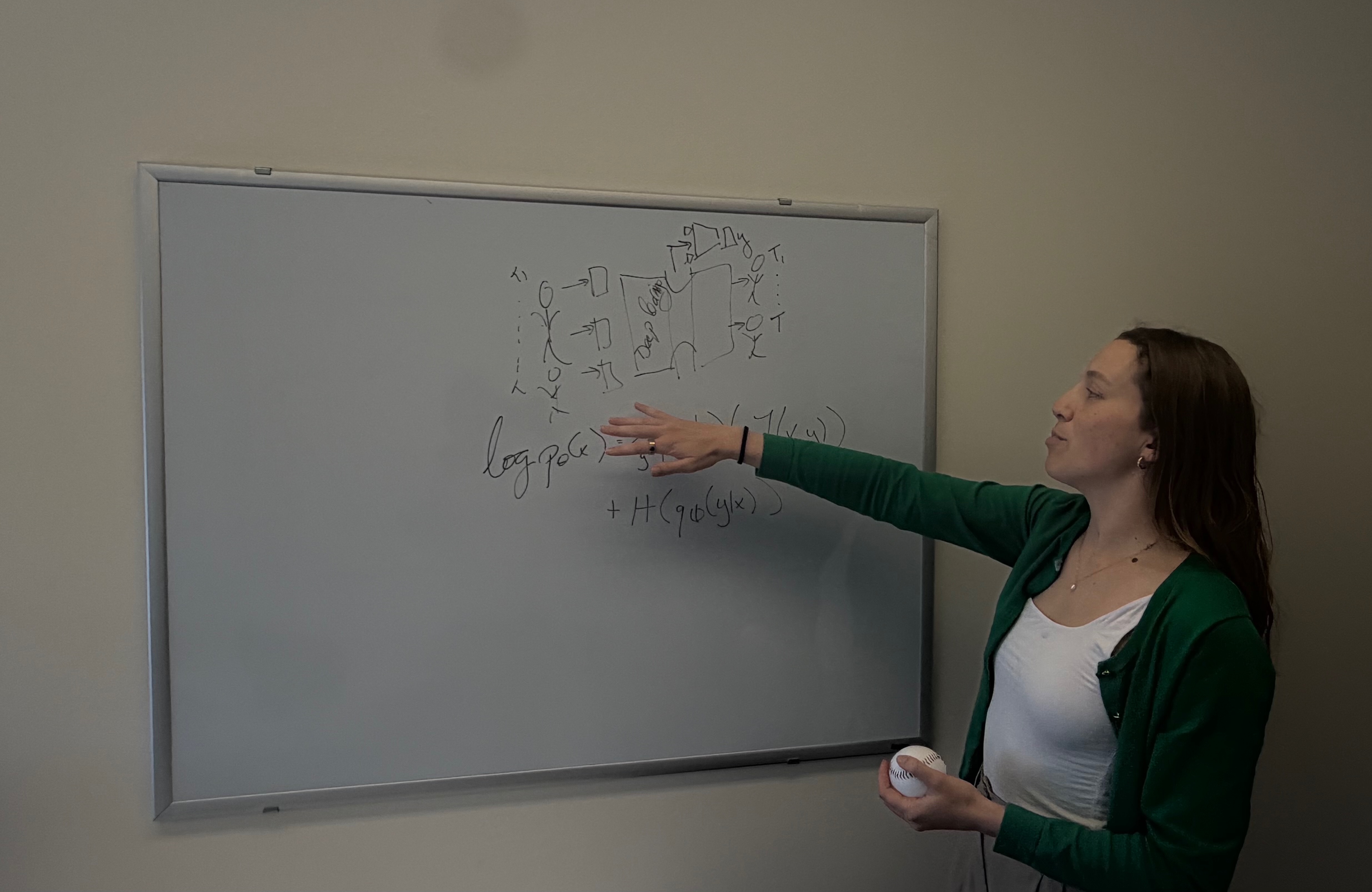 Mathilde Papillon stands in profile next to a whiteboard, gesturing with her left hand toward a mathematical equation. She holds a baseball in her right hand. The whiteboard displays a hand-drawn diagram showing input figures flowing into a 'Deep Learning' block and resulting in output figures, along with an equation regarding log probability written below.