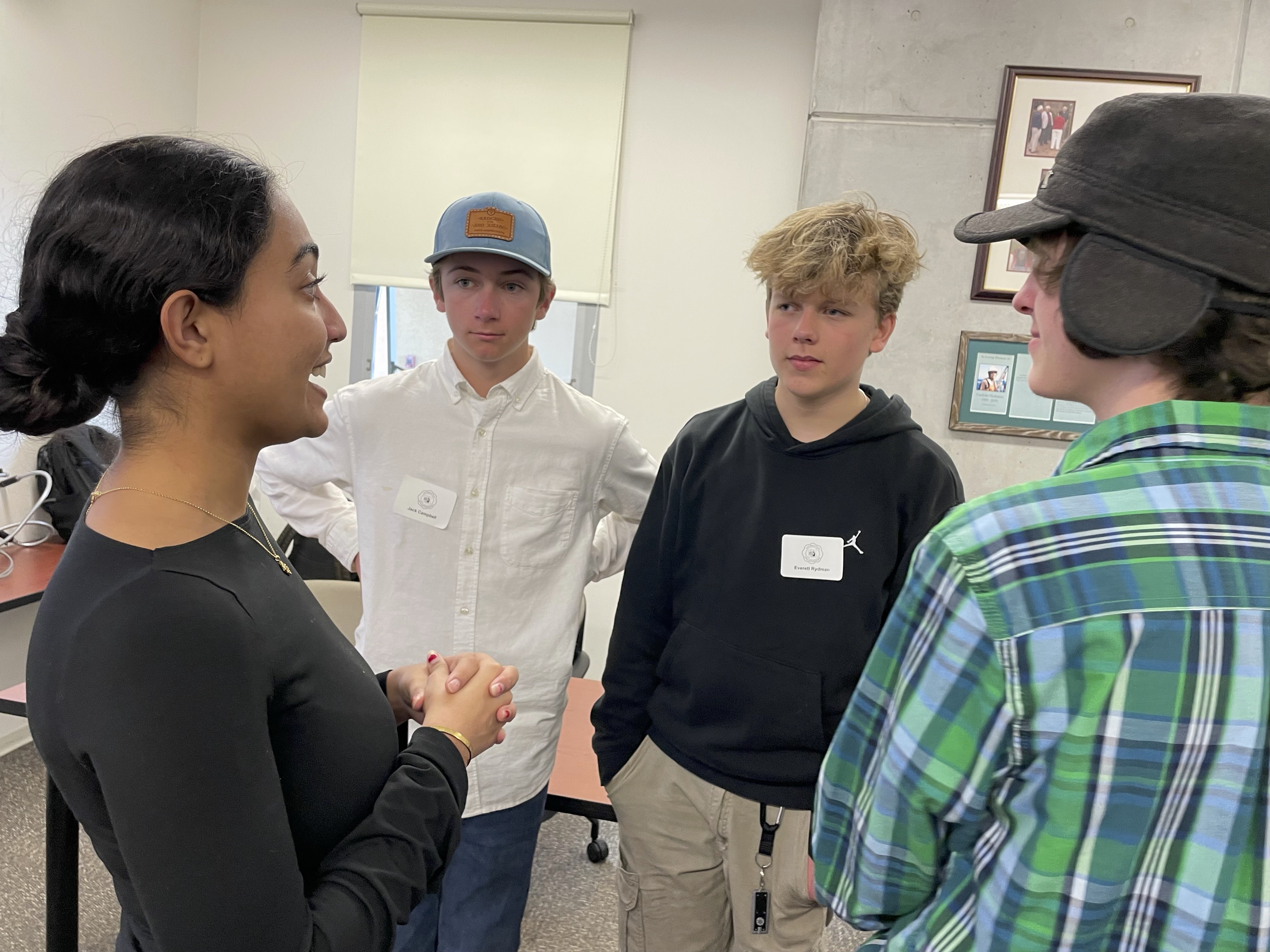 Three students listen attentively as a UCSB researcher explains a concept during a science fair lab tour.