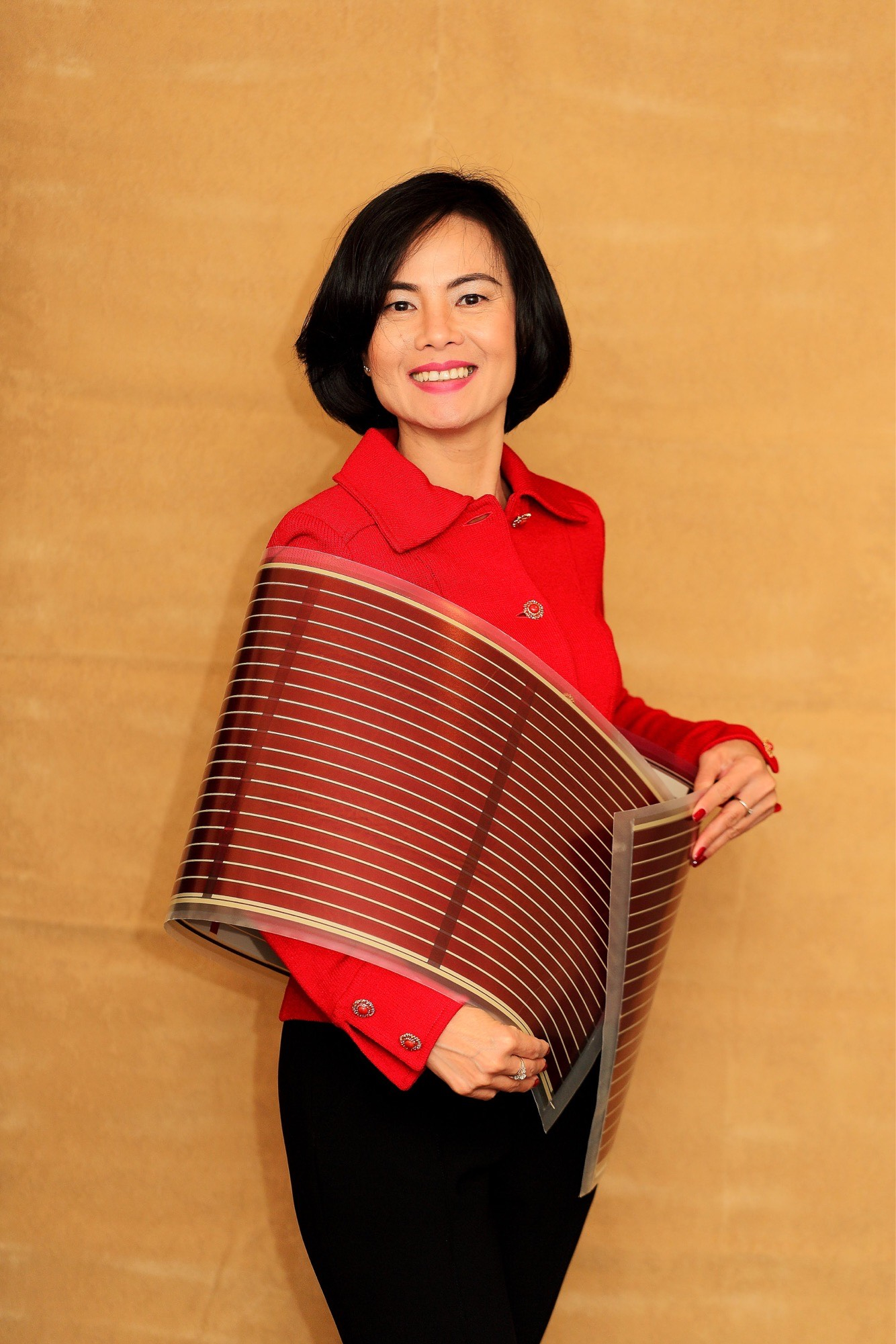 Thuc-Quyen Nguyen smiles while holding a large flexible sheet of organic solar-cell material.