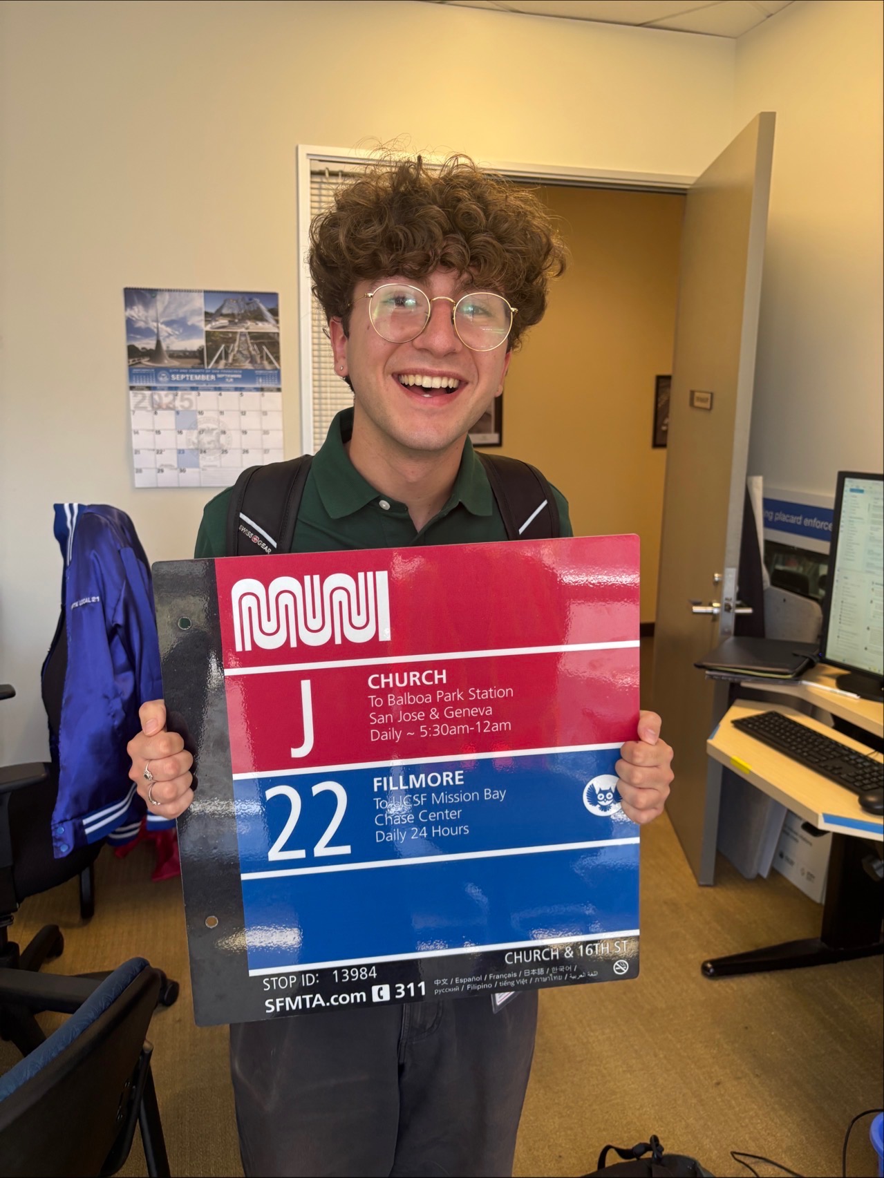 Andrew Tolu, a UCSB Geography/Sociology triple major, holding a San Francisco MUNI bus stop sign during his internship