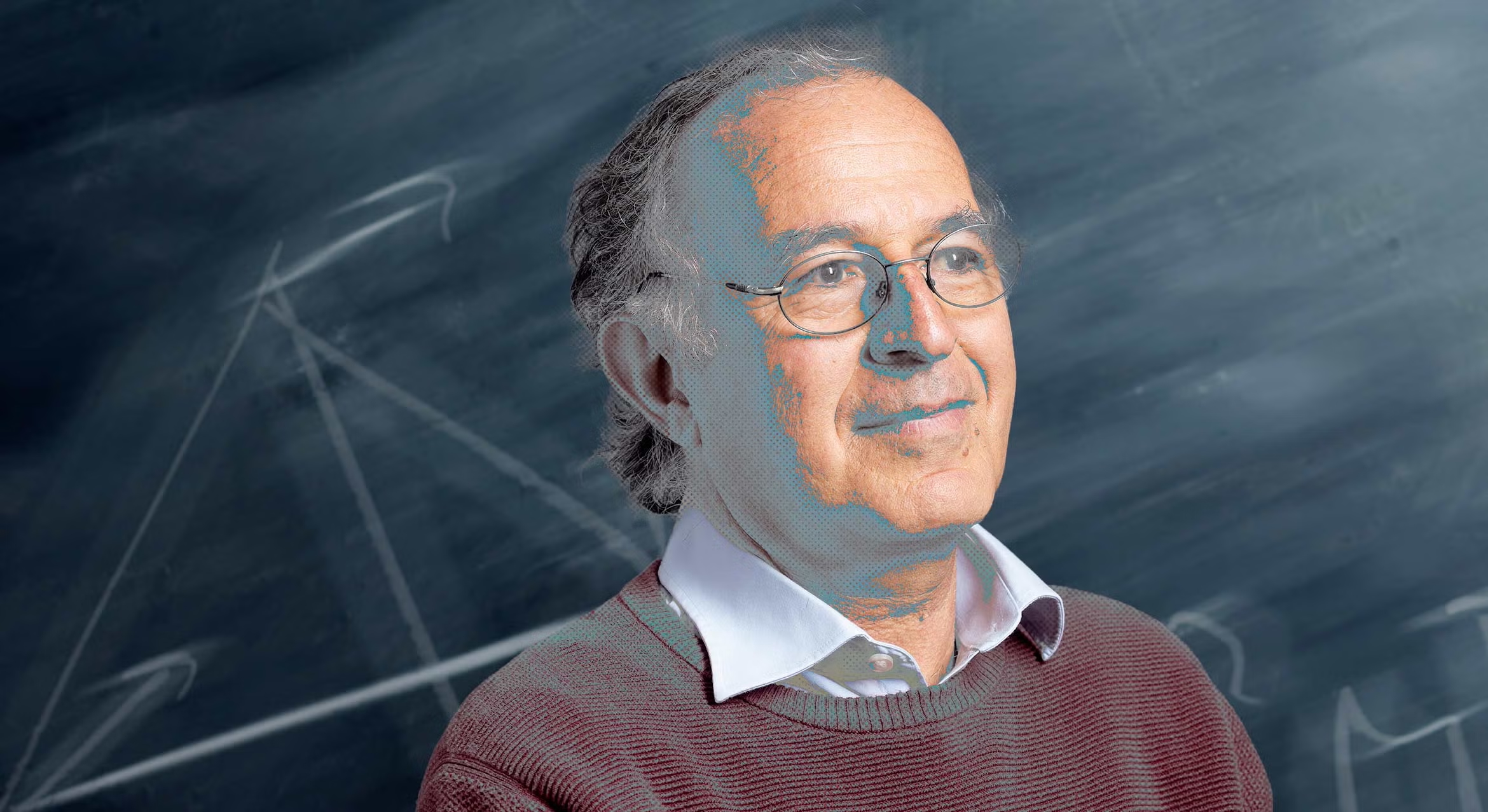 Head and shoulders portrait of Boris Schraiman. He is wearing wire-rimmed glasses, a maroon sweater over a white collared shirt, and has gray hair. He is smiling slightly and looking off to the right. The background is a dark chalkboard with faint white diagrams and arrows.