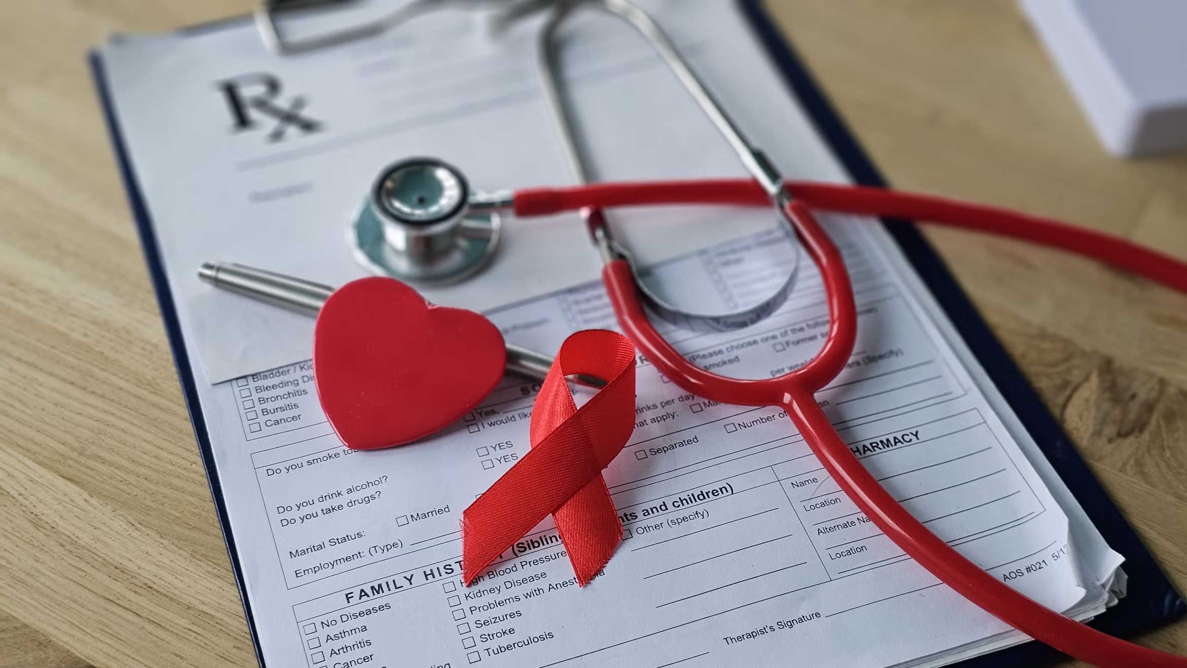 Stethoscope, family history medical intake form and a red awareness ribbon.