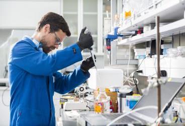 A person in a science lab using a pipette
