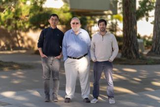 Assistant Professor Yang Hai, Emeritus Professor Stanley Parsons, and Assistant Professor Lior Sepunaru standing together on a walkway at the UC Santa Barbara campus.